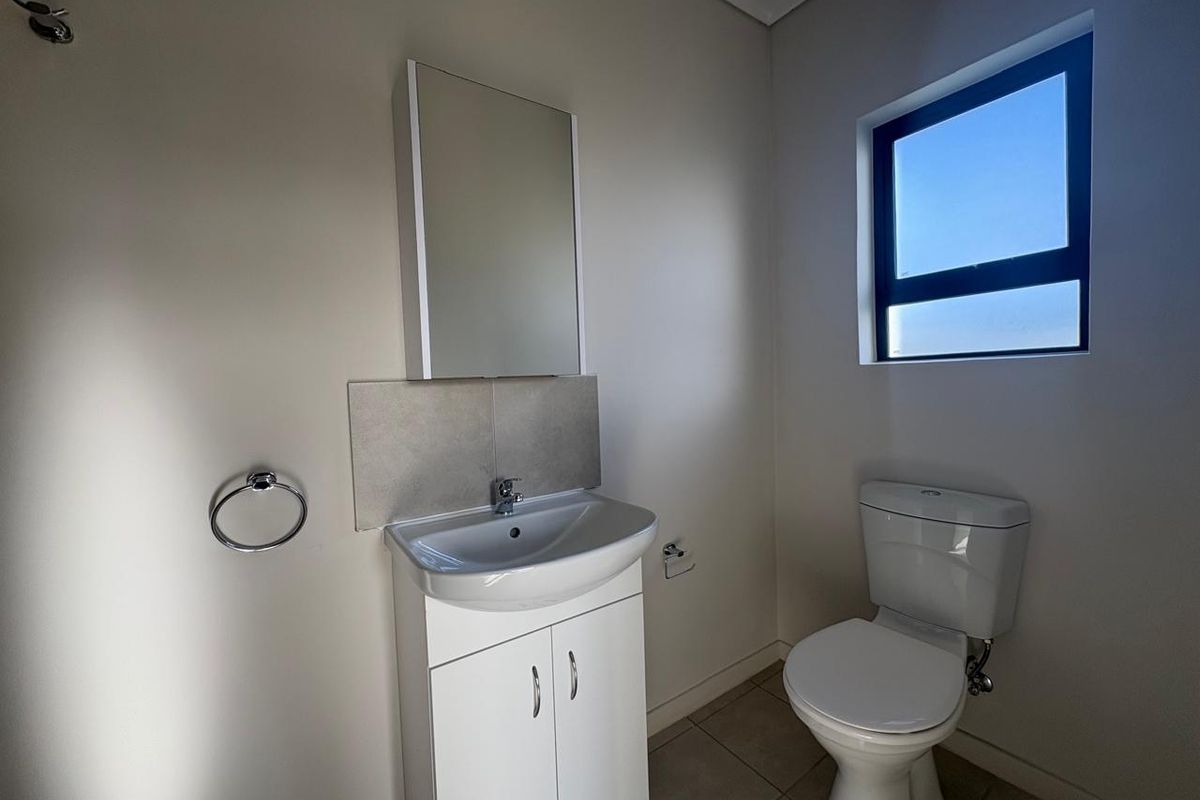 A clean and functional bathroom featuring a vanity cabinet with a basin, a wall-mounted mirror cabinet, and a standard toilet.
