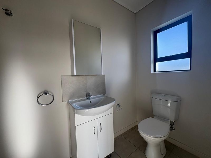 A clean and functional bathroom featuring a vanity cabinet with a basin, a wall-mounted mirror cabinet, and a standard toilet.