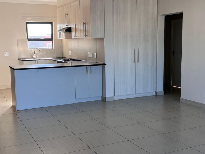 Open plan kitchen and living area featuring modern built-in cabinetry, a functional kitchen island, and neutral tiled flooring throughout.