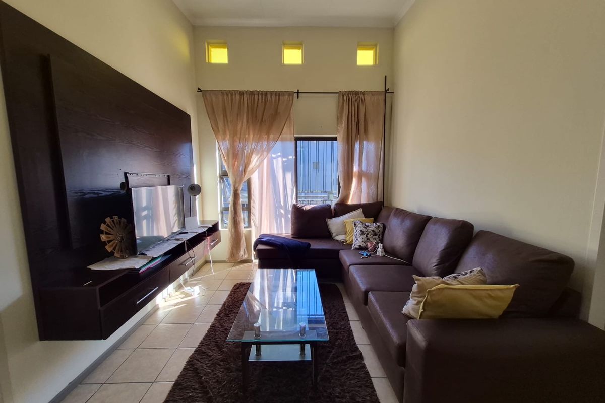 A living room featuring tiled flooring, a built-in dark wood media console, and high-level clerestory windows providing natural light.