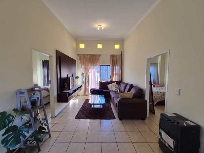 Spacious living room featuring tiled flooring, a built-in media console, and high ceilings with clerestory windows, providing access to an outdoor area.