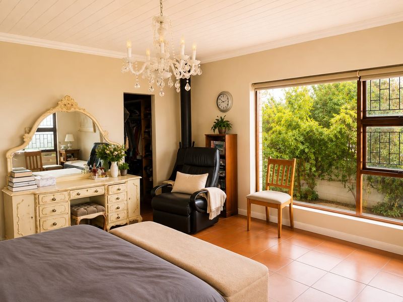 Spacious bedroom featuring tiled flooring, a wood-burning fireplace, a walk-in closet, and large windows overlooking the garden.