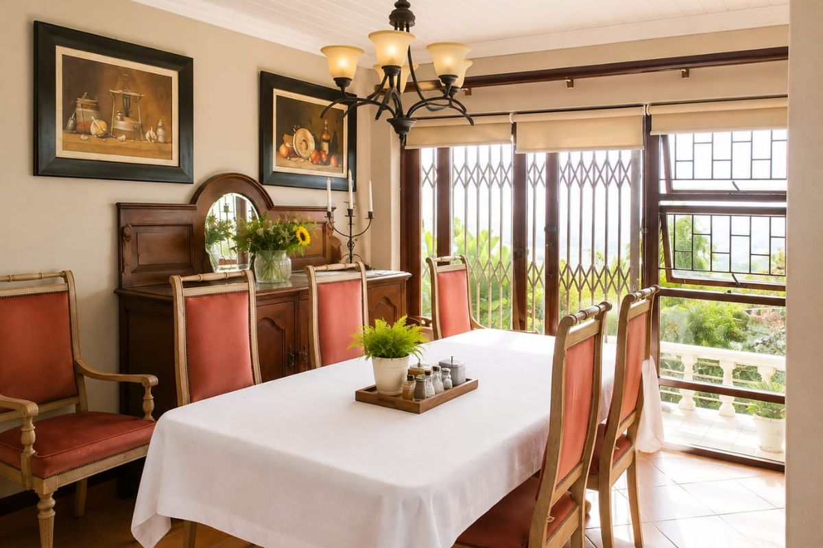 A well-maintained dining room featuring tiled flooring, crown molding, and large sliding glass doors with security gates, providing access to an outdoor area.