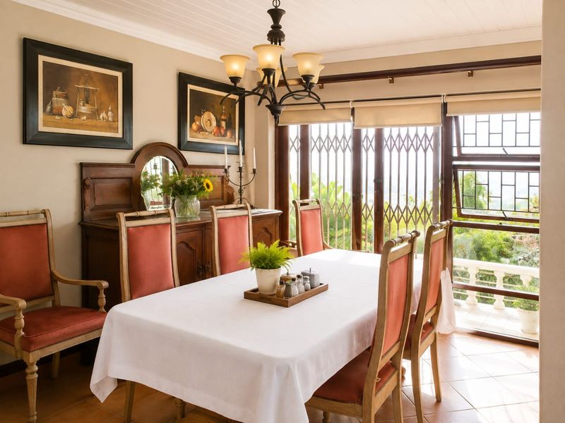 A well-maintained dining room featuring tiled flooring, crown molding, and large sliding glass doors with security gates, providing access to an outdoor area.