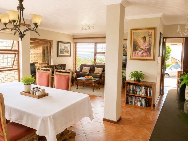 Spacious open-plan living and dining area featuring terracotta floor tiles, a tongue and groove ceiling, and large windows providing natural light.