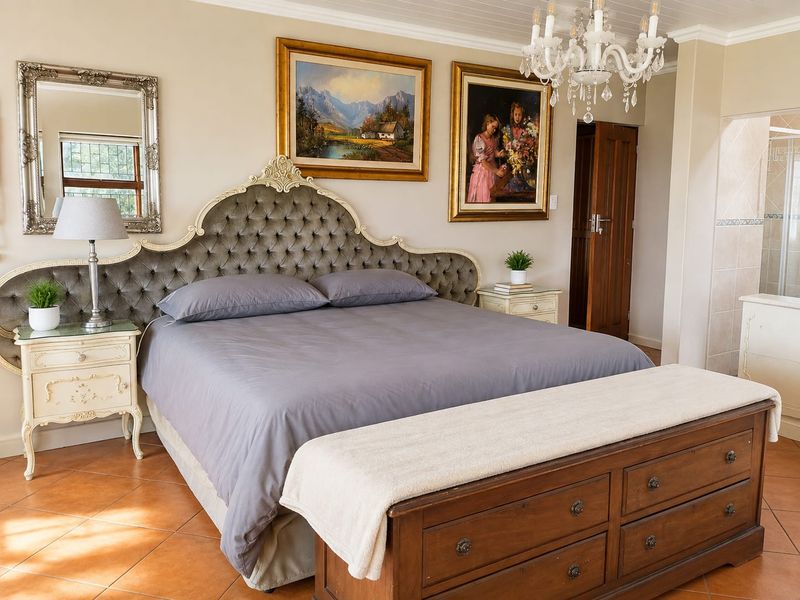 Spacious bedroom featuring tiled flooring, a decorative chandelier, and direct access to an en-suite bathroom.