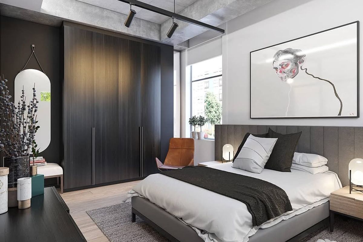 Modern bedroom featuring a sleek built-in wardrobe, exposed concrete ceiling with track lighting, and large windows providing ample natural light.