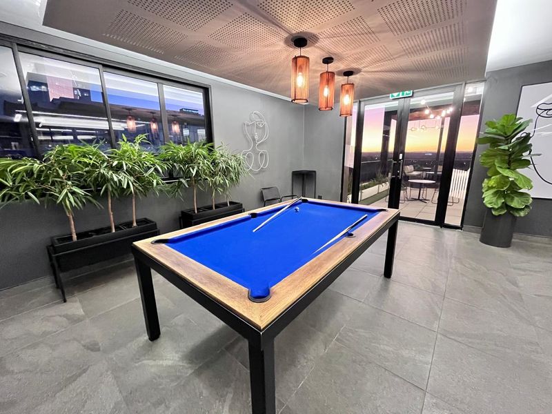 Modern clubhouse area featuring large format floor tiles, acoustic ceiling panels, and direct access to an outdoor balcony through sliding glass doors.