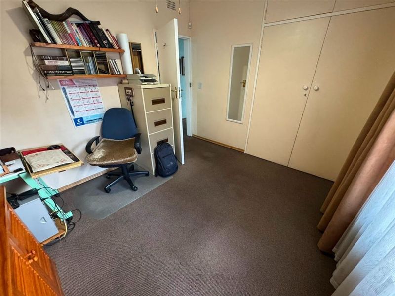 A bedroom featuring built-in cupboards and carpeted flooring, offering a functional space that could benefit from cosmetic updates.