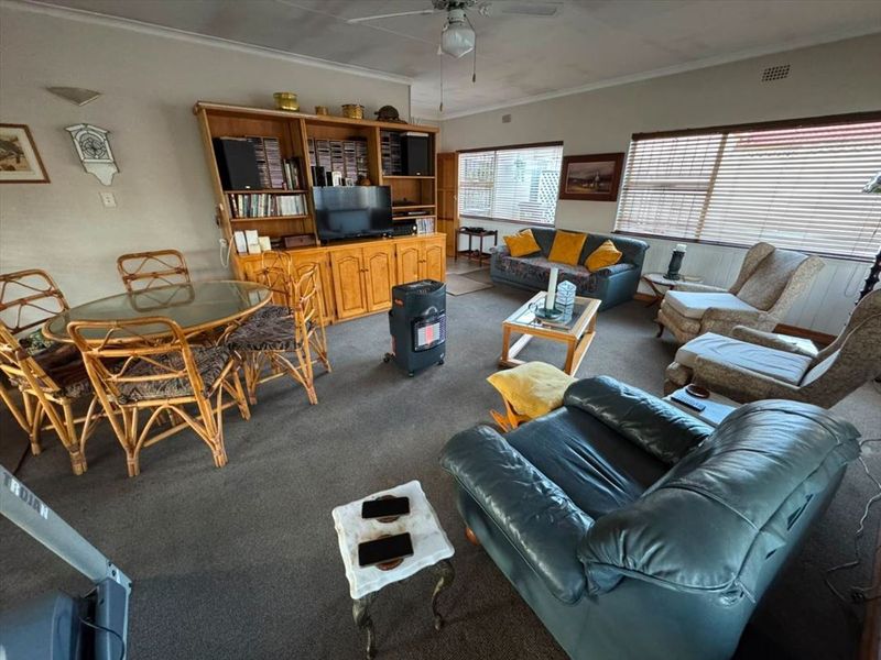 Spacious living room featuring built-in cabinetry, ceiling fan, and large windows with venetian blinds, offering a functional layout for family living.