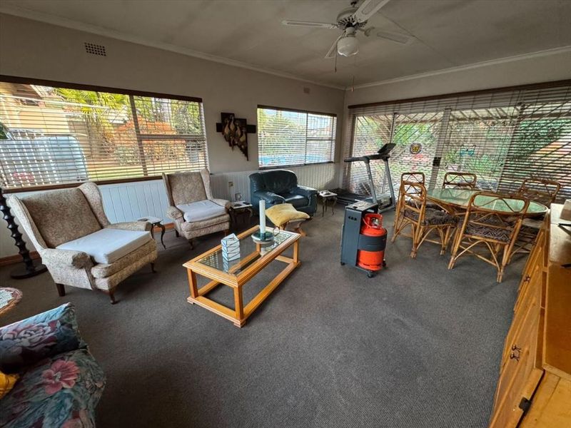 Spacious living area featuring large windows, sliding glass doors to the exterior, and a ceiling fan, offering a bright and functional layout.