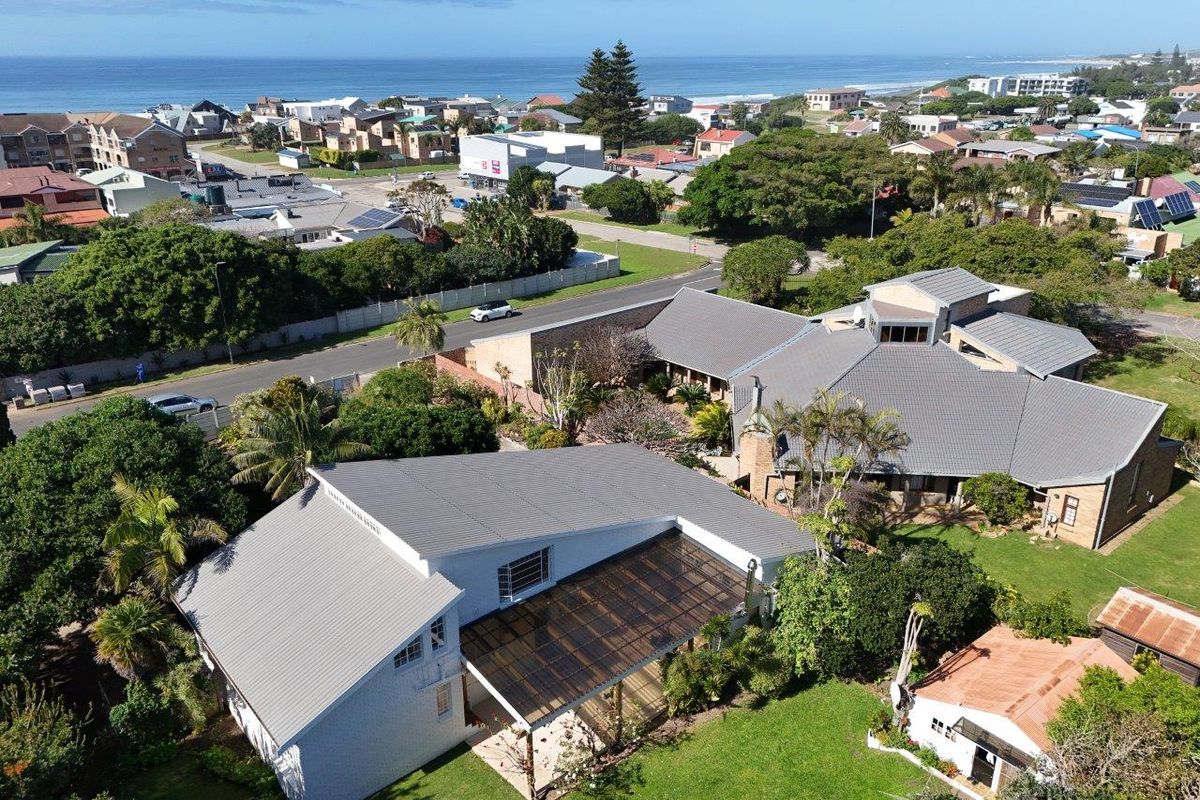 Aerial view of the property showcasing the roof structure, covered patio, and surrounding landscaped garden in a coastal neighborhood setting.
