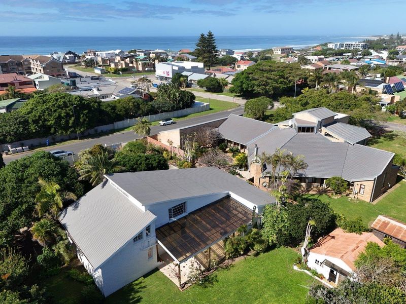 Aerial view of the property showcasing the roof structure, covered patio, and surrounding landscaped garden in a coastal neighborhood setting.