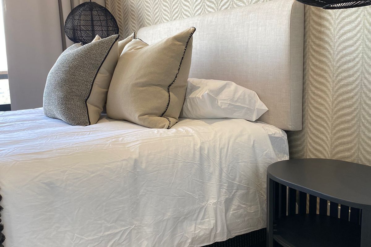 A well-appointed bedroom featuring neutral textured wallpaper, tiled flooring, and modern curtain tracks, creating a clean and contemporary living space.