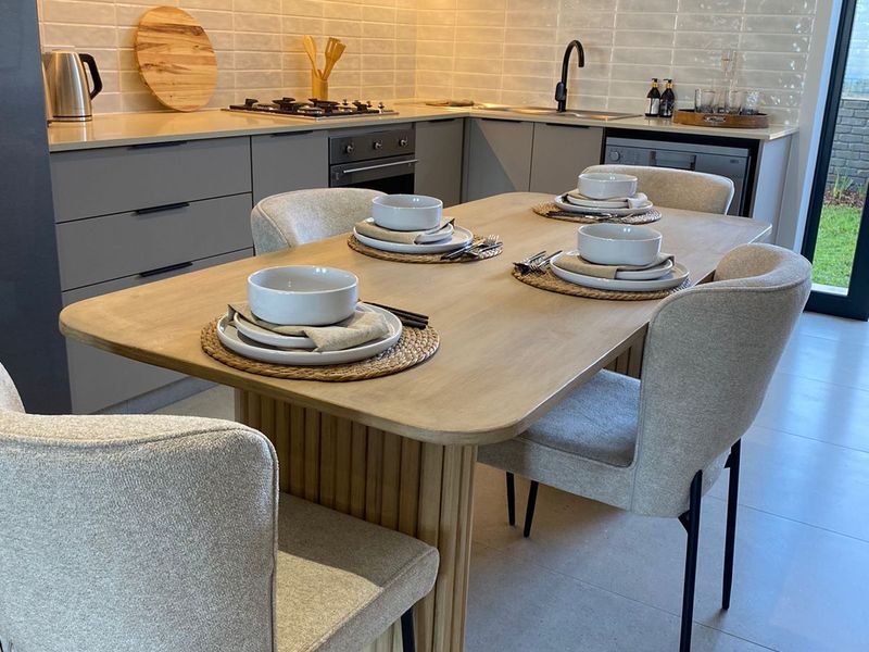 Modern open-plan kitchen and dining area featuring sleek grey cabinetry, stone countertops, subway tile backsplash, and integrated lighting.