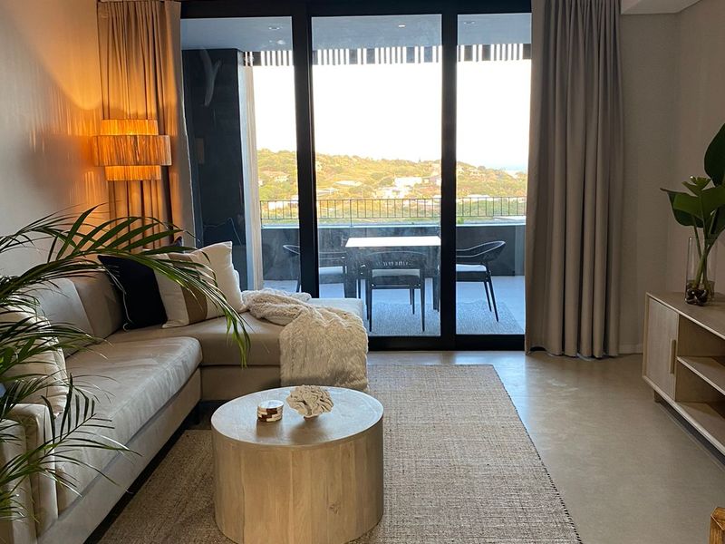 Modern living room featuring polished concrete floors and large sliding glass doors that open onto a private balcony with scenic views.