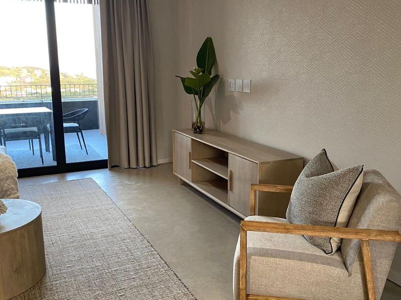 Modern living room featuring neutral textured wallpaper, sleek tiled flooring, and large sliding glass doors providing access to an outdoor balcony area.