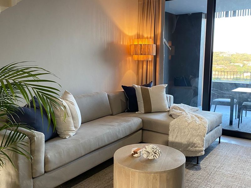 Modern living room featuring a staircase, recessed lighting, and large sliding glass doors that open onto a balcony with scenic views.