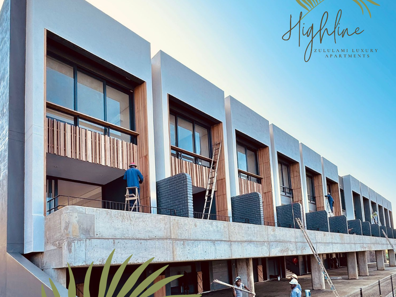 Exterior view of a luxury apartment development under construction, featuring modern concrete architecture, timber detailing, and private balconies.