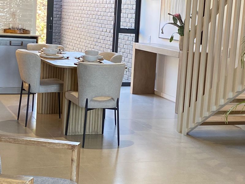 Modern open-plan living and dining area featuring sleek tiled floors, a contemporary timber slat staircase, and seamless access to an outdoor patio space.