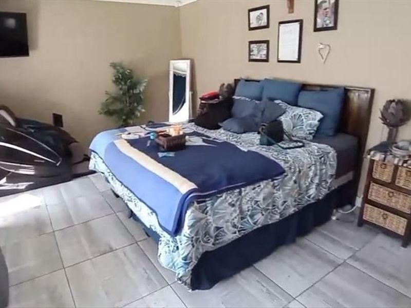 A bedroom featuring tiled flooring and a wall-mounted television bracket, offering a functional space with neutral wall tones.