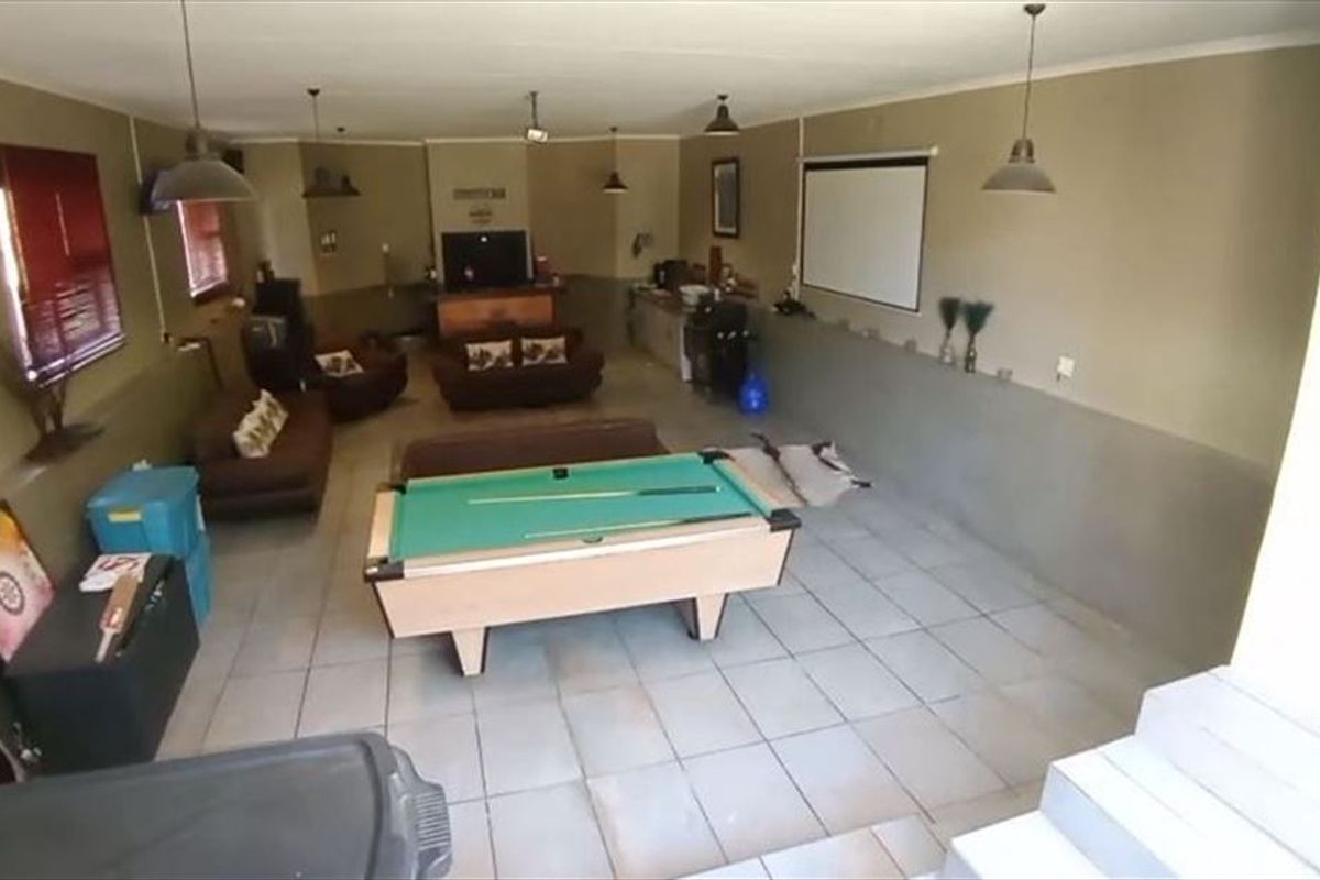 Spacious entertainment area featuring tiled flooring, a built-in bar counter, and a projector screen, suitable for a games room or casual living space.