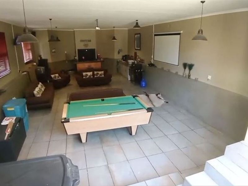 Spacious entertainment area featuring tiled flooring, a built-in bar counter, and a projector screen, suitable for a games room or casual living space.