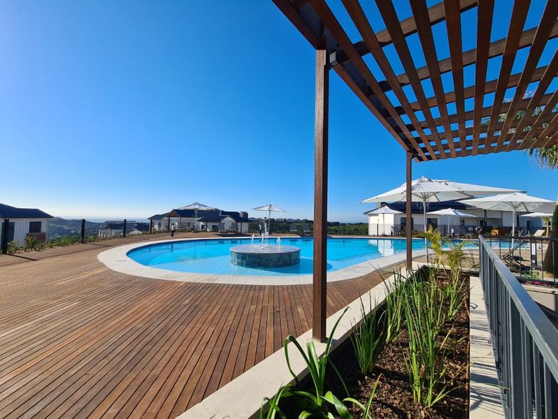 A well-maintained outdoor pool area featuring timber decking, a central water fountain, and a timber pergola, offering a pleasant space for relaxation.