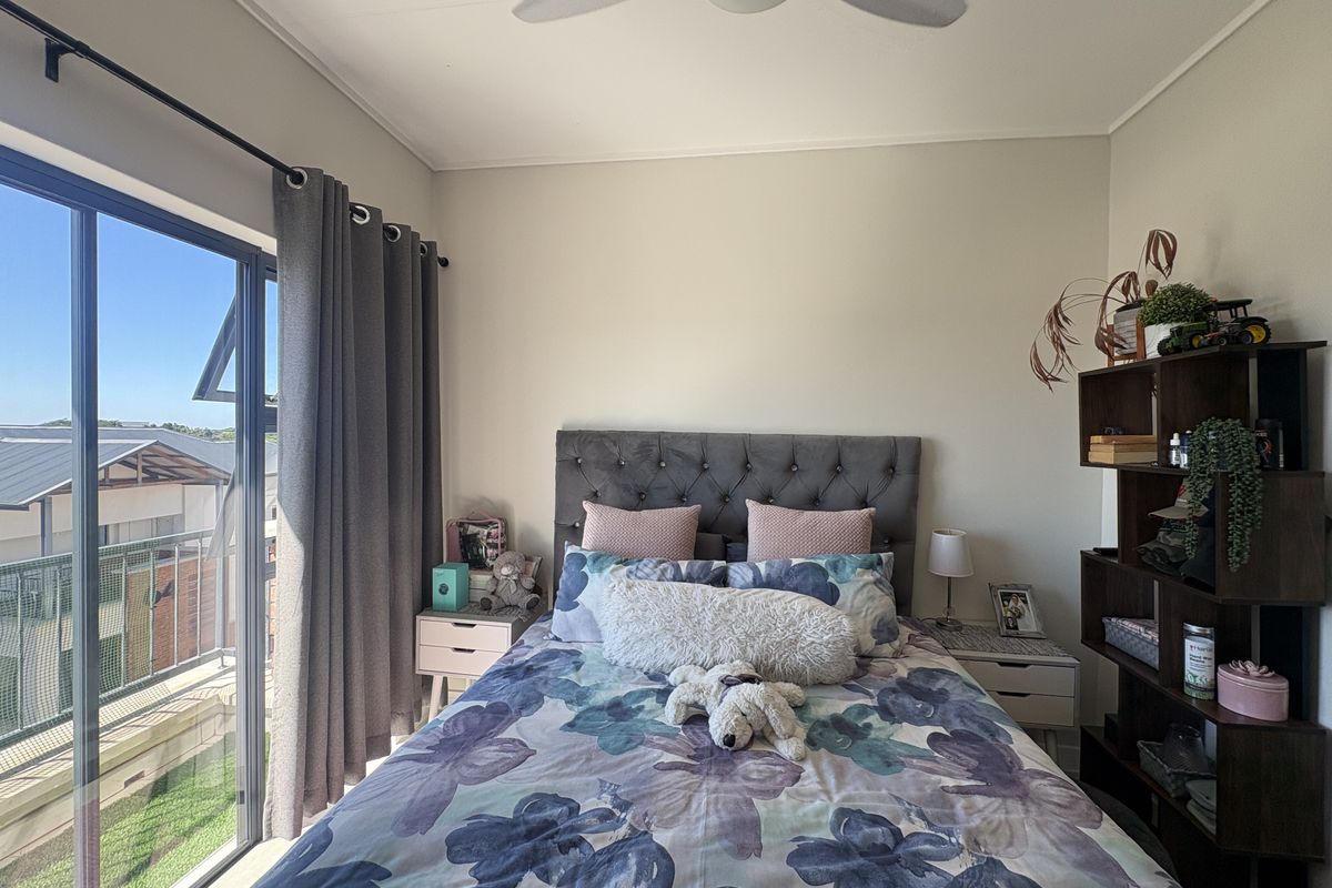 A well-lit bedroom featuring a ceiling fan and a large sliding glass door providing access to an outdoor balcony area.