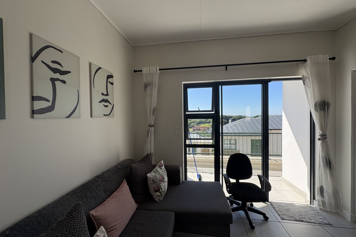 A bright living room featuring tiled flooring and a large sliding glass door that provides access to an outdoor balcony area.