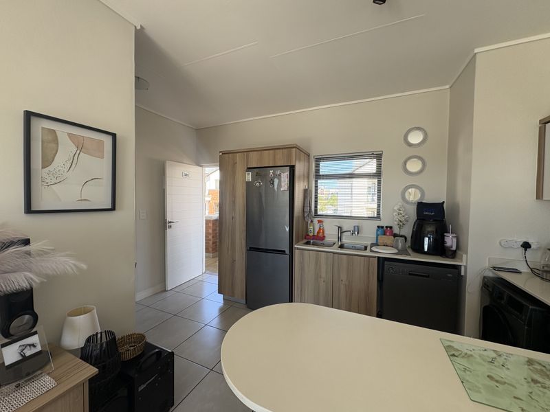 A functional kitchen area featuring built-in cabinetry, a double sink, and tiled flooring, with direct access to an exterior doorway.