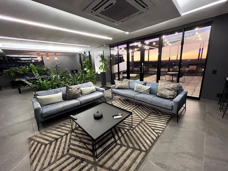 Modern, well-lit living area featuring large glass sliding doors leading to an outdoor patio, recessed ceiling lighting, and ducted air conditioning.