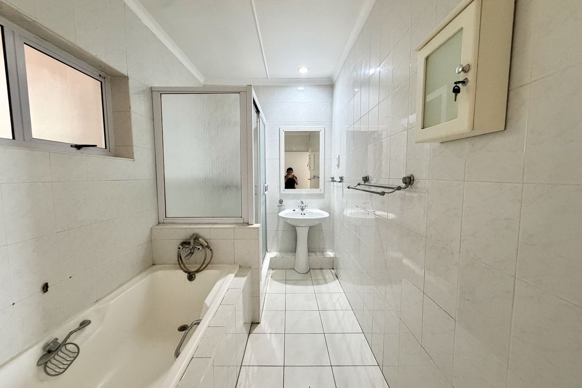 A functional bathroom featuring a pedestal basin, bathtub, and separate shower enclosure with white tiled finishes throughout.