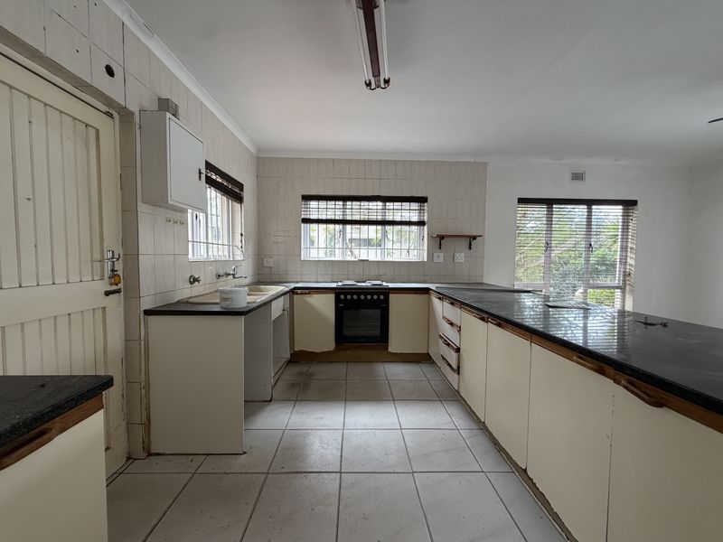 Spacious kitchen featuring built-in cabinetry, stone countertops, and a built-in oven, offering a functional layout ready for modern updates and renovation.