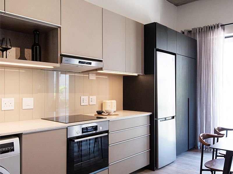 Modern kitchen featuring sleek cabinetry, stone countertops, integrated appliances, and a striking exposed concrete ceiling, creating a contemporary and functional living space.