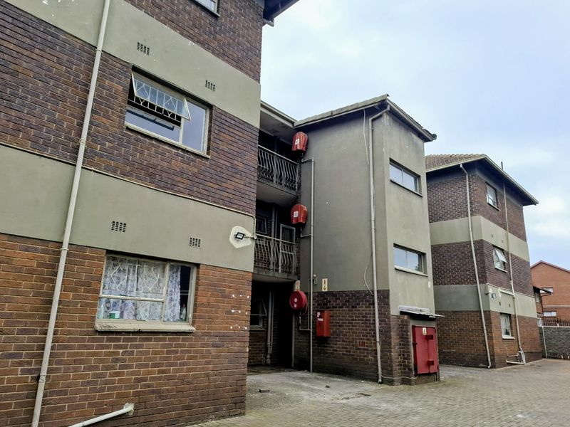 Exterior view of a multi-story apartment complex featuring brick and plaster facade, metal balustrades, and installed fire safety equipment.