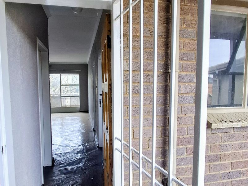 Entrance area featuring a security gate, timber door, and direct access to the interior hallway with visible flooring wear.