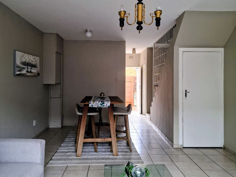 Open plan living and dining area featuring tiled flooring, a staircase with a metal balustrade, and neutral wall tones.