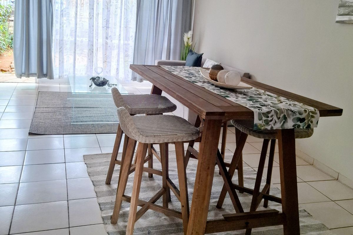 A living area featuring neutral tiled flooring and a large sliding glass door providing access to the outdoor space.