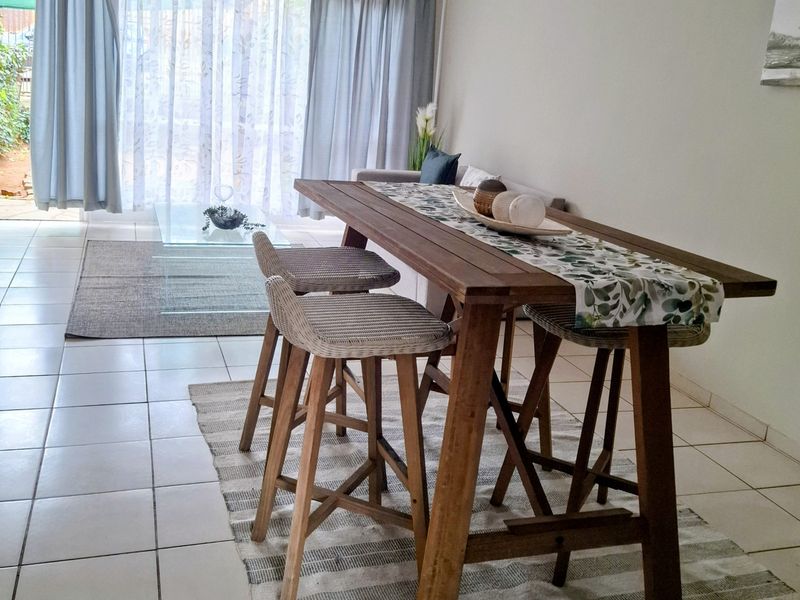 A living area featuring neutral tiled flooring and a large sliding glass door providing access to the outdoor space.