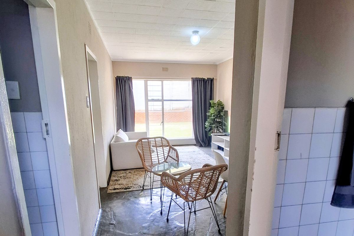 A living area featuring tiled flooring and a large window, providing natural light. The space is ready for a modern update.