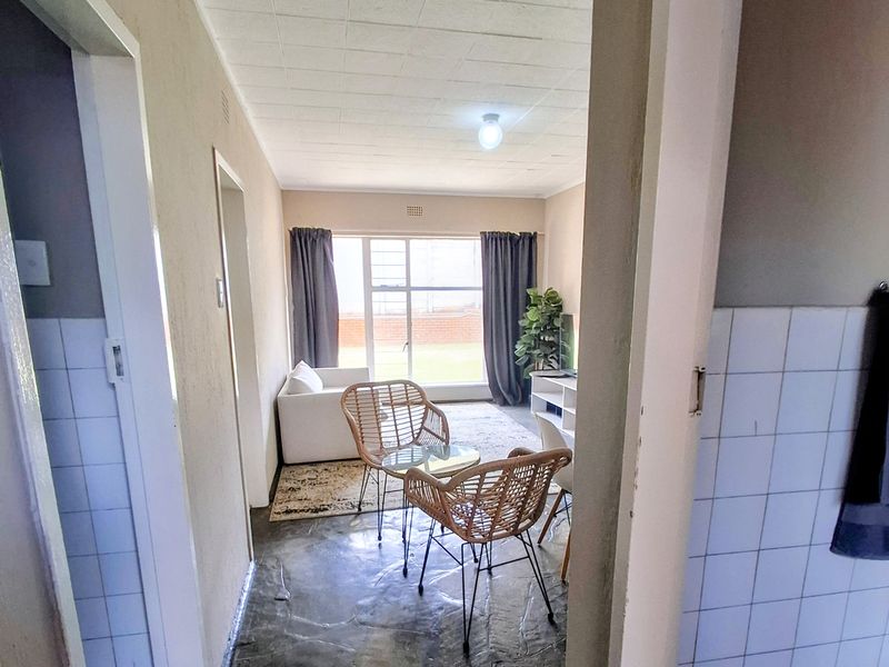 A living area featuring tiled flooring and a large window, providing natural light. The space is ready for a modern update.