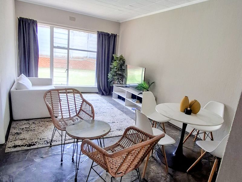 Open plan living and dining area featuring large windows, tiled flooring, and a neutral color palette, offering a functional and versatile living space.