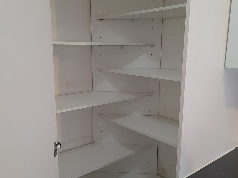 A functional built-in corner pantry or scullery storage unit with adjustable shelving, providing efficient storage space within the kitchen area.