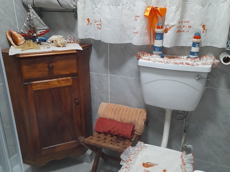A compact bathroom featuring grey ceramic wall and floor tiles, a standard toilet cistern, and a shower enclosure.
