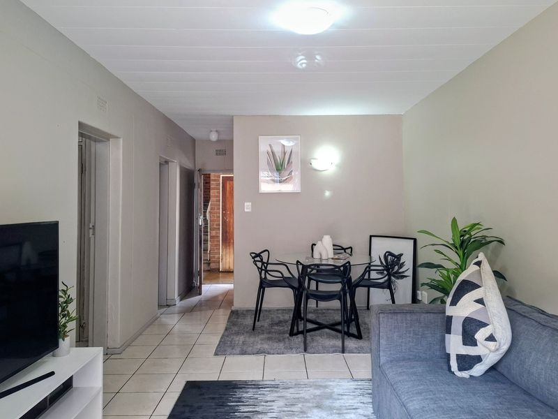 Open-plan living and dining area featuring neutral wall tones, tiled flooring, and direct access to the hallway and entrance.