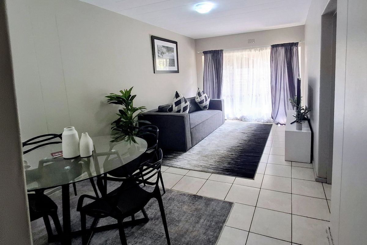 Open-plan living and dining area featuring neutral tiled flooring and a large sliding glass door providing natural light.