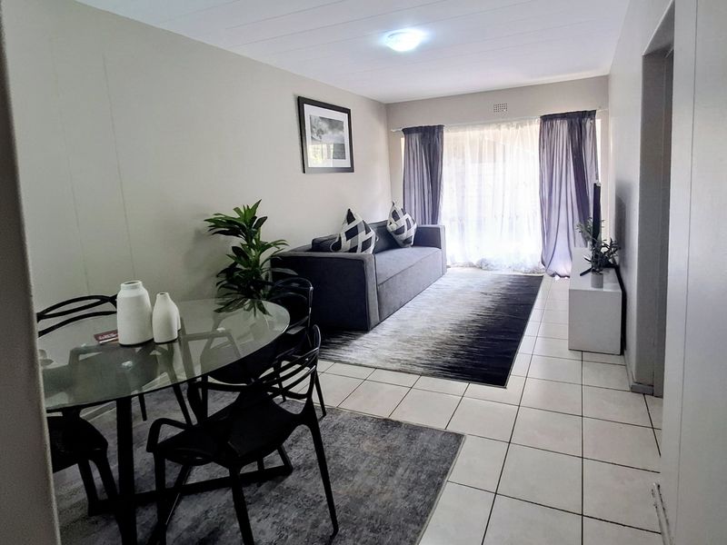 Open-plan living and dining area featuring neutral tiled flooring and a large sliding glass door providing natural light.