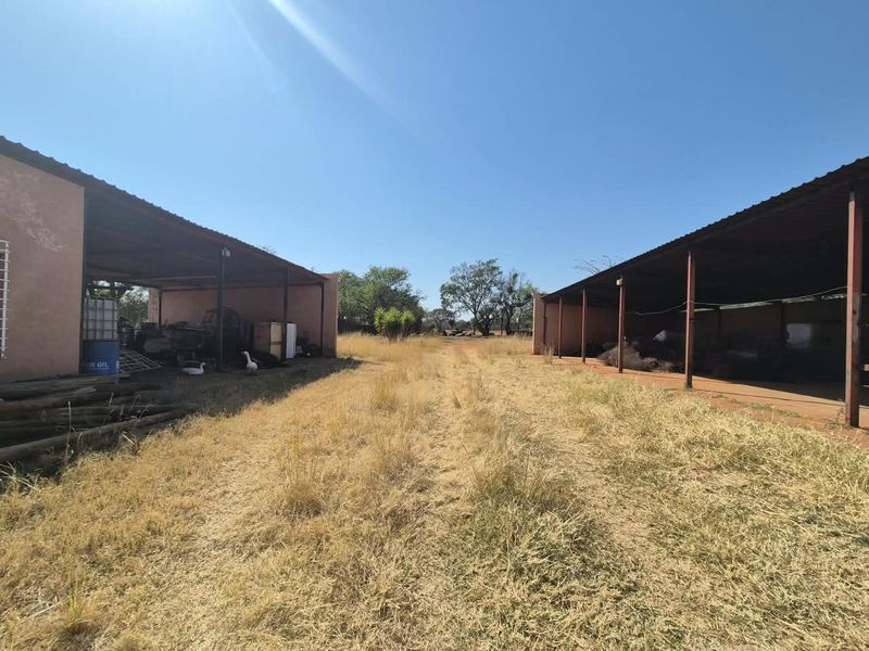 Two large open-sided farm storage sheds with metal roofing, providing ample space for agricultural equipment or general storage on the property.