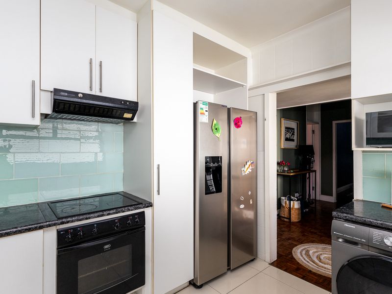 A functional kitchen featuring white cabinetry, a tiled backsplash, built-in oven and hob, and dedicated space for a large refrigerator.